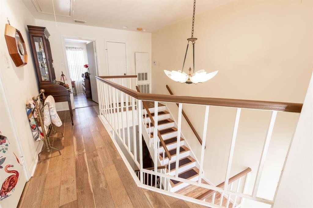 Balcony overlooking the interior atrium by the front door. In the background on this level is the primary bedroom with its ensuite bath.