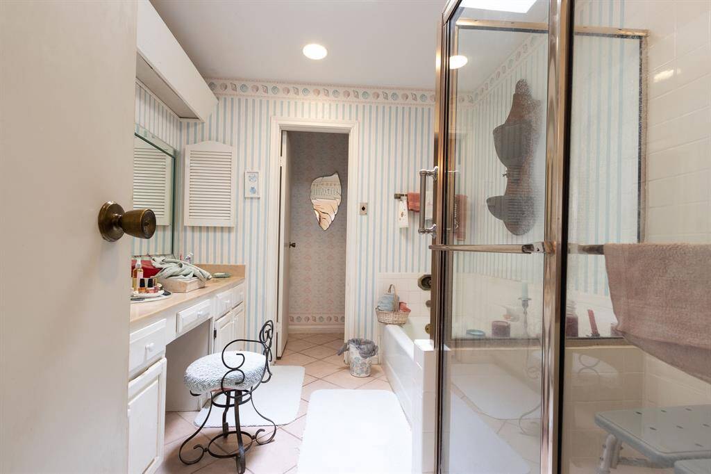 Primary ensuite bath with two-sink vanity on the left and separate shower and tub on the right.  Commode closet in the background.