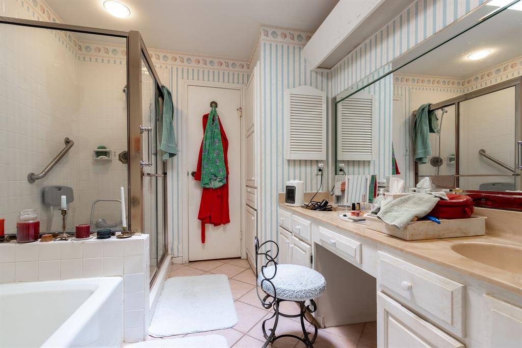 Primary ensuite bath with tile floor, long vanity with two sinks. Separate tub and shower stall.