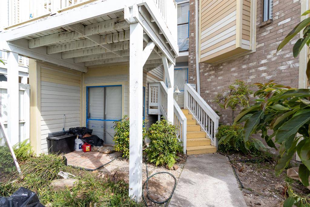 Looking into the front yard with the yellow steps up to the front door. On the left is the sliding glass door to the downstairs bedroom.