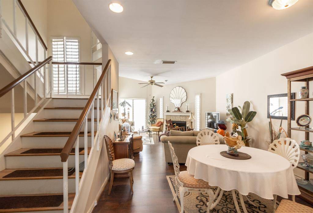 Living & dining area with fireplace in the background. Staircase on the left going upstairs and there is a staircase going downstairs to the front door, another bedroom and bath and the two car garage.