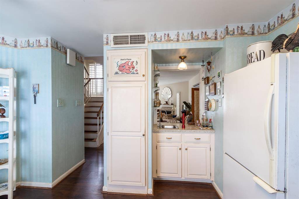 View within the kitchen with the refrigerator on the right. Pass-through to the dining area in the foreground. Dining and living area in the far background.