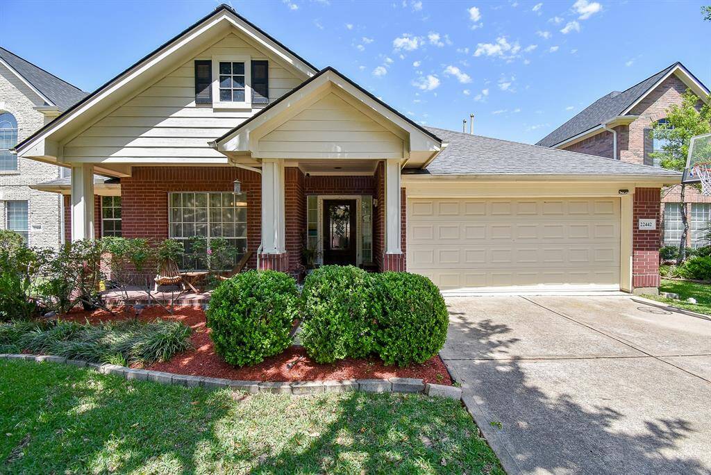 Charming single-story home with a welcoming front porch and manicured landscaping. It features a brick and siding exterior, a two-car garage, and a cozy sitting area. Ideal for buyers seeking a comfortable, inviting residence.
