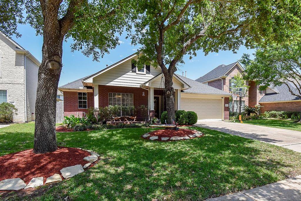 The front yard features mature trees and a lush green lawn, creating a serene and inviting atmosphere. Perfect for family living.