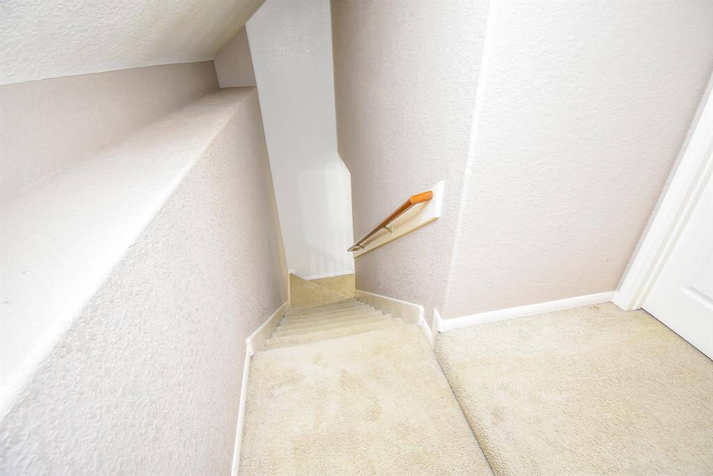 This photo shows the staircase with a wooden handrail leading to another level, ideal for a compact home setting.