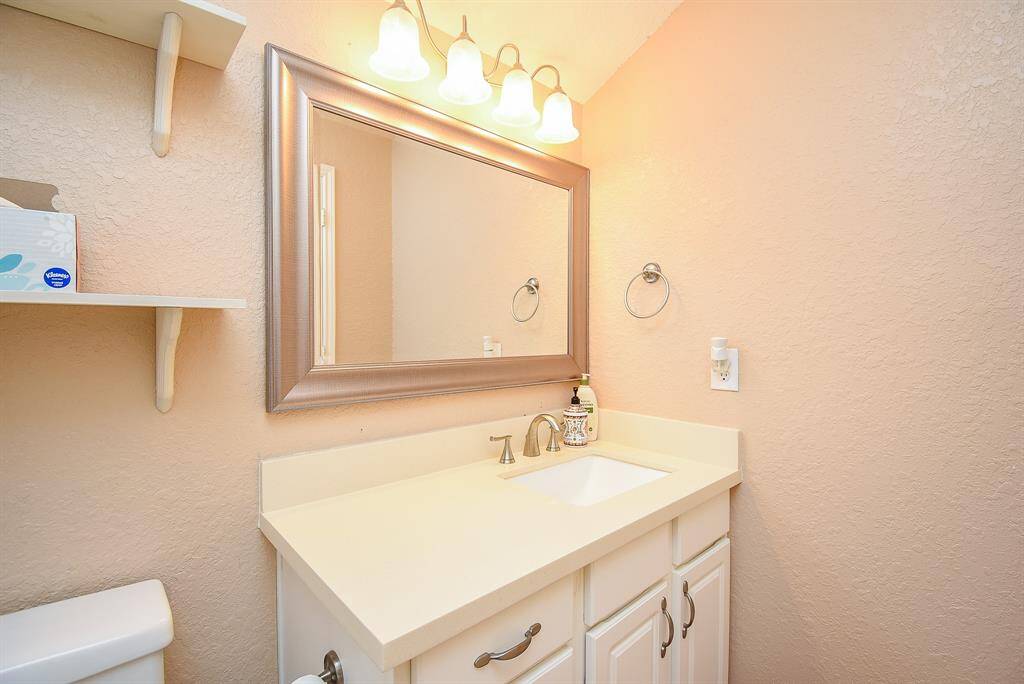 Cozy bathroom with a single sink vanity, elegant framed mirror, bright lighting, and practical shelving. Ideal for a compact and functional space.