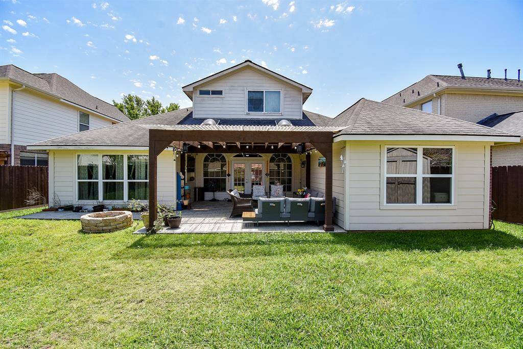 This photo shows a charming backyard with a covered patio area perfect for outdoor relaxation. The house features a well-maintained exterior and a spacious lawn, ideal for family activities and entertaining guests.