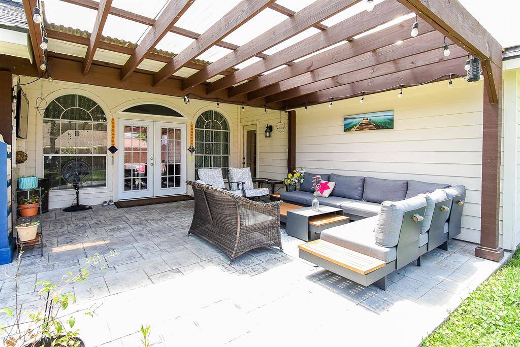 This inviting outdoor patio features a pergola, elegant French doors, and comfortable seating, perfect for relaxation and entertaining.