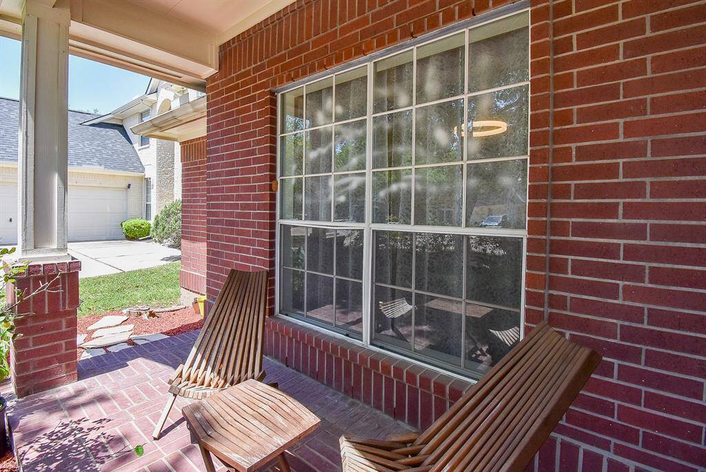 Charming front porch with brick details. Large window offers a view of the front yard and driveway, creating a welcoming entrance.