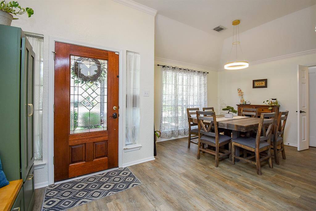 Bright dining area with wood flooring and high ceiling, a modern light fixture, and a large window for natural light.