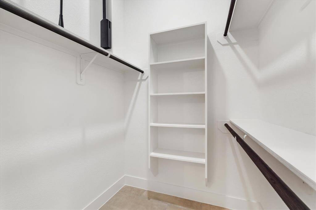 Modern en suite with stand-up shower and neutral finishes throughout, as well as a linen closet for additional storage.