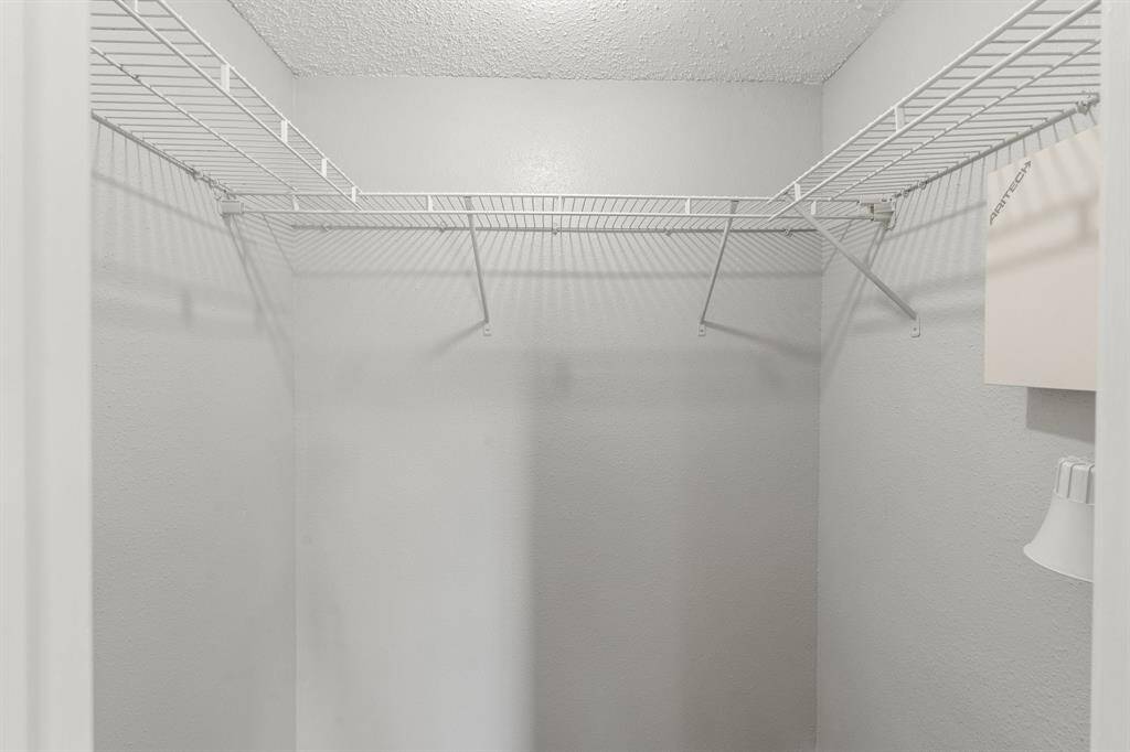 A look into the Primary Spacious Walk-in Closet showcasing an abundance of hanging storage and shelf space.