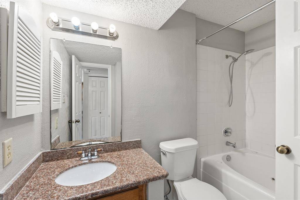 Secondary bathroom offers granite countertop, sleek finishes, and tub/shower combo with tile surround.