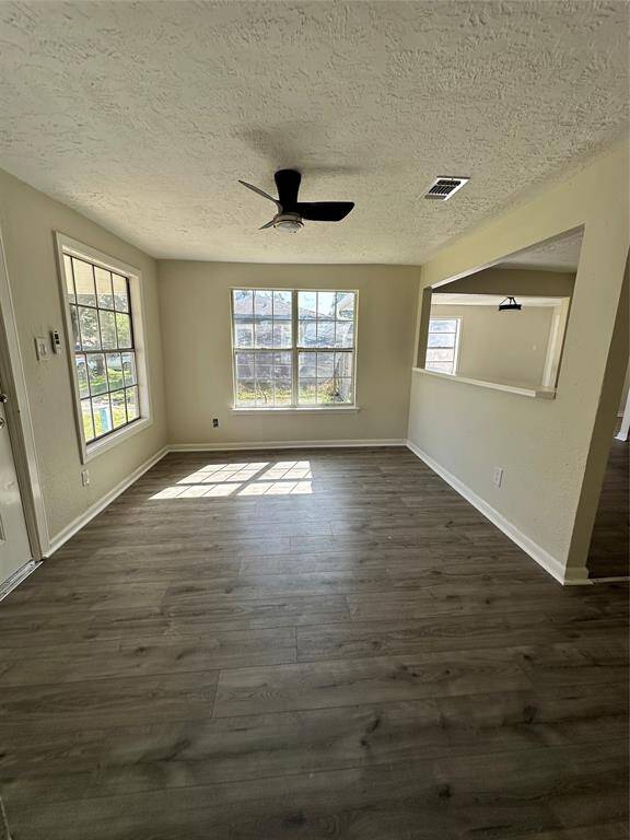 Bright and inviting front room featuring modern flooring, a ceiling fan, and ample natural light, perfect for entertaining.