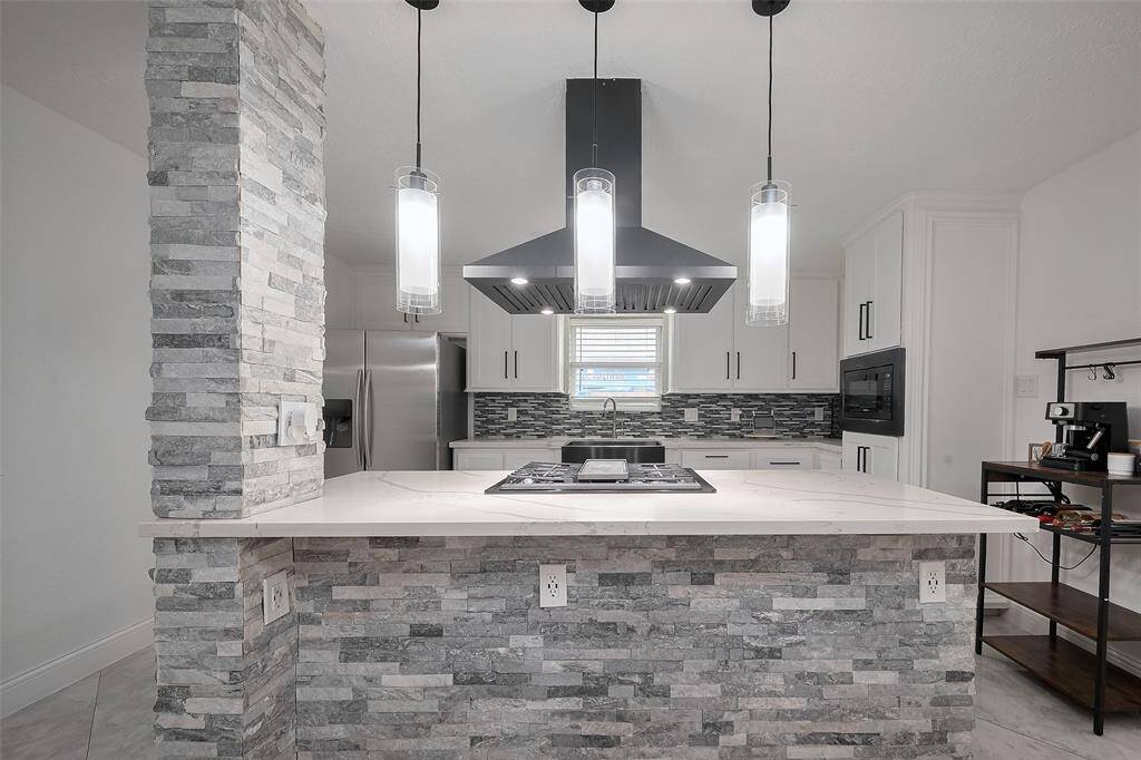 The kitchen island with pendant lighting doubles as a breakfast bar