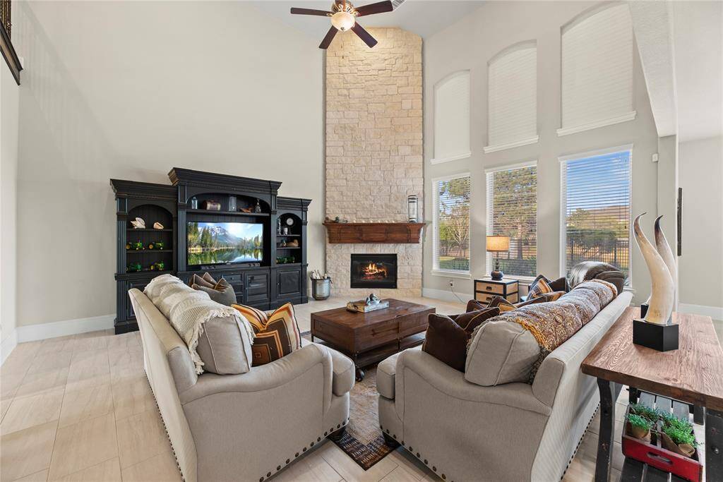 The expansive living room impresses with soaring two-story ceilings and walls of windows that flood the space with natural light. Anchored by a dramatic two-story stone fireplace in the corner, this grand yet inviting space is perfect for both everyday living and unforgettable entertaining.