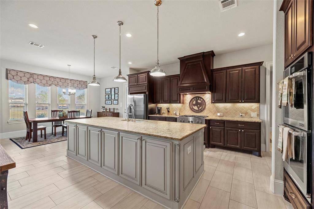 Your chef-inspired kitchen is ready to impress! This beautifully designed space boasts gleaming granite countertops, a coordinating stone backsplash, and sleek stainless steel appliances. The rich cabinetry, enhanced with updated hardware, is perfectly complemented by under-cabinet lighting and recessed lighting, creating a bright and inviting ambiance. At the heart of it all, a sprawling island, providing additional workspace and storage.