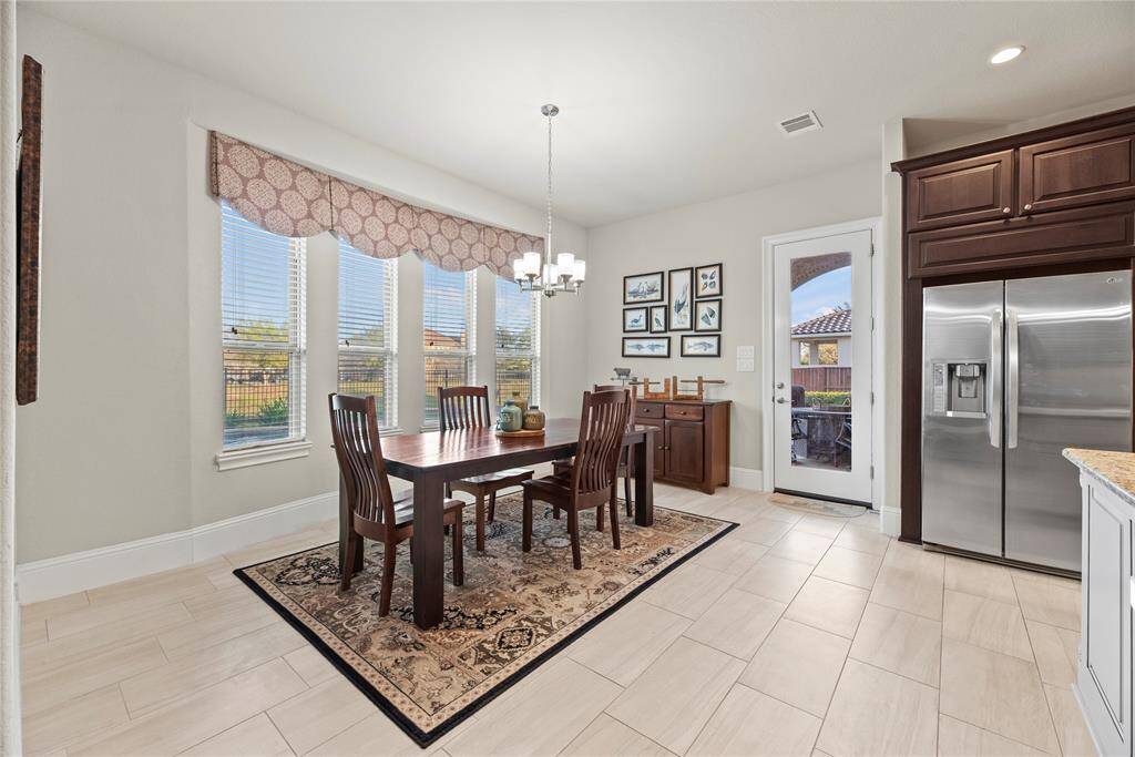The breakfast room is ideal for a full-sized table and features easy care tile floors, overhead chandelier and large bright windows overlooking the picturesque backyard.