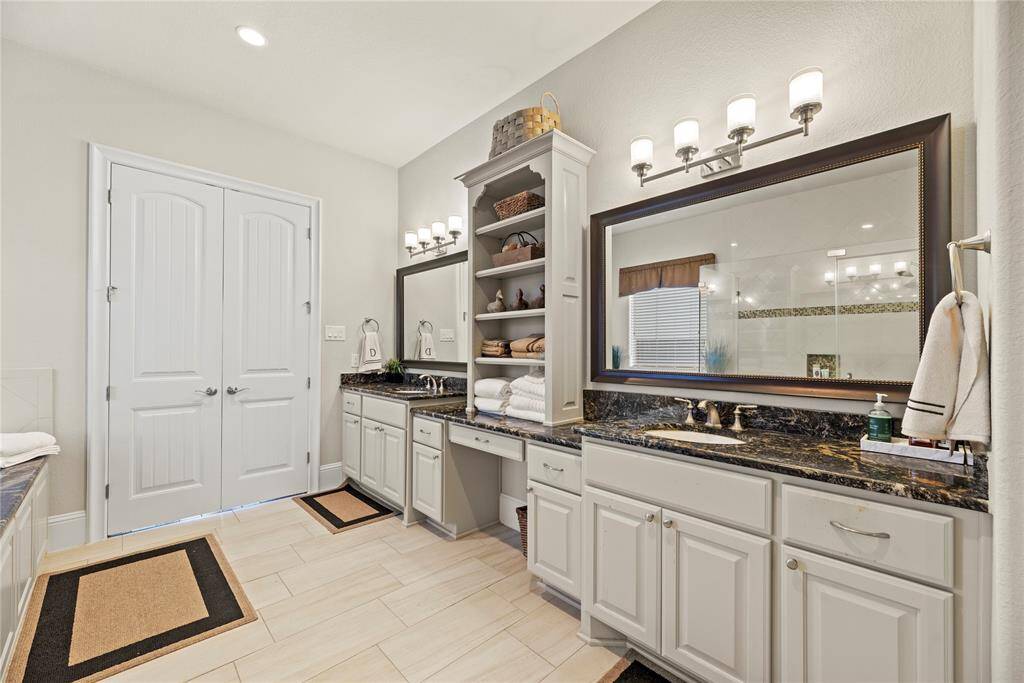 The primary bath features exquisite dual vanities, providing ample personal space along with an abundance of custom cabinetry for seamless organization.