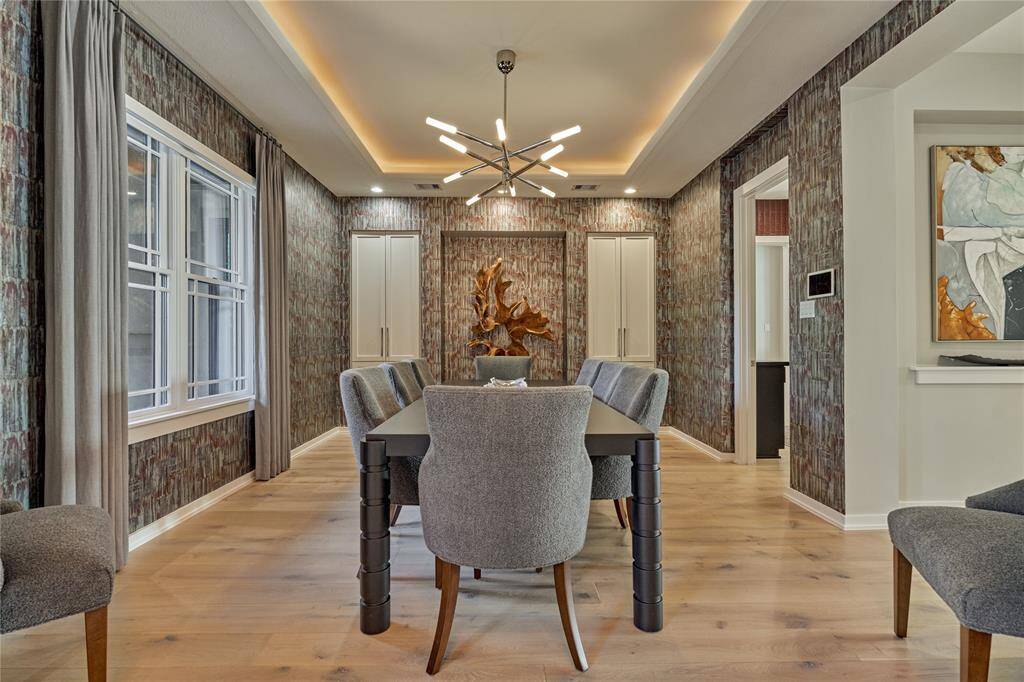 What better way to dazzle you and your guests than with this divine dining room boasting of opulent lighting, custom glam wallpaper and crisp white built-in cabinetry.