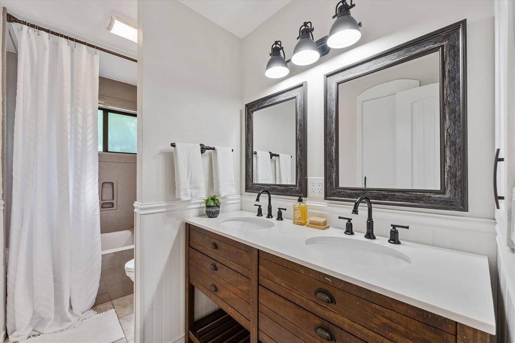Modernized secondary bathroom featuring a stylish double vanity and convenient pull-out laundry drawer.