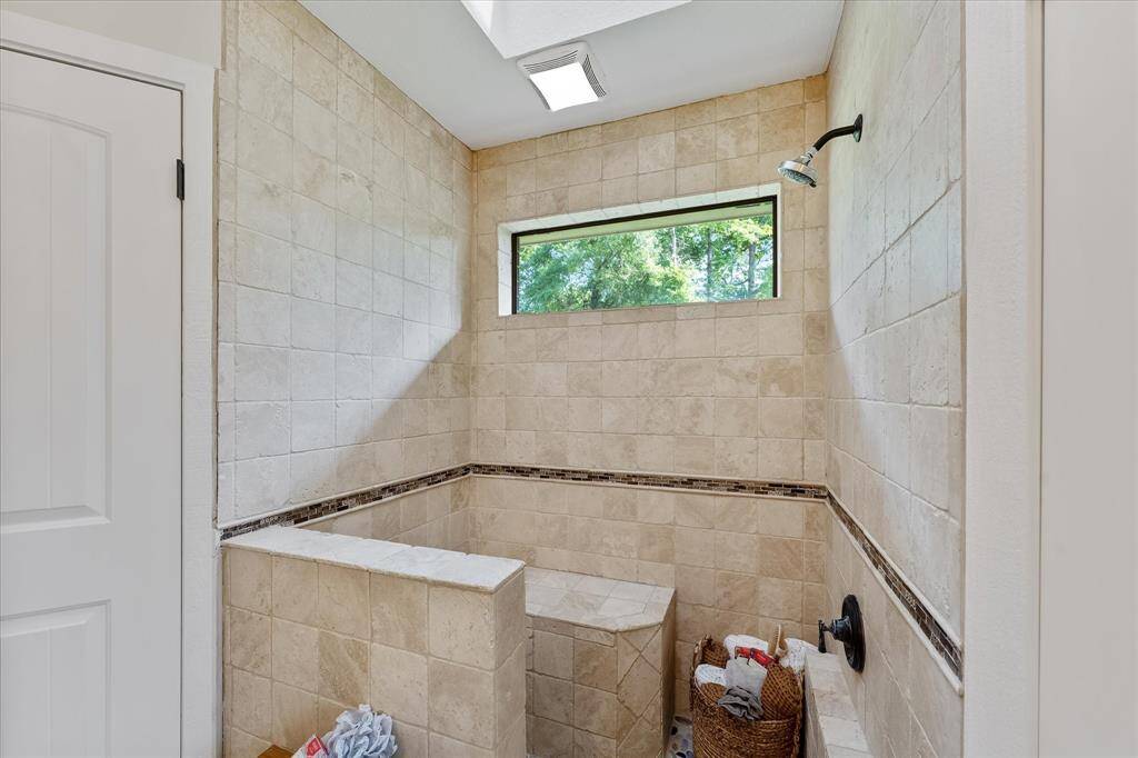 Luxurious en-suite primary bathroom features a tiled walk-in shower with built-in seating.