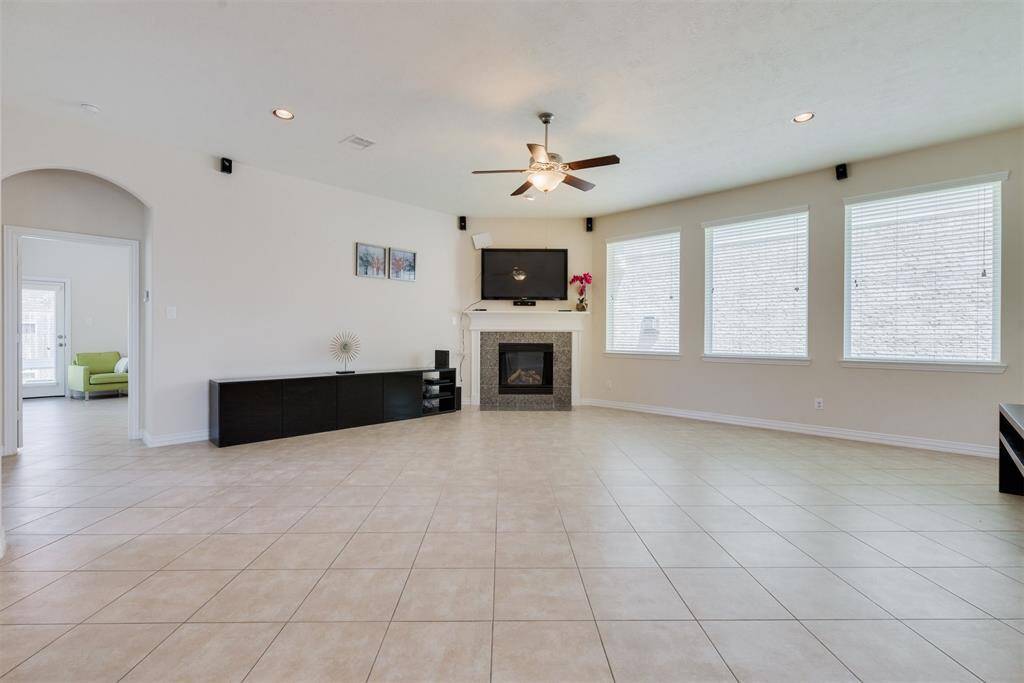 Huge living room full of natural light, bright fixtures, and cozy fireplace.