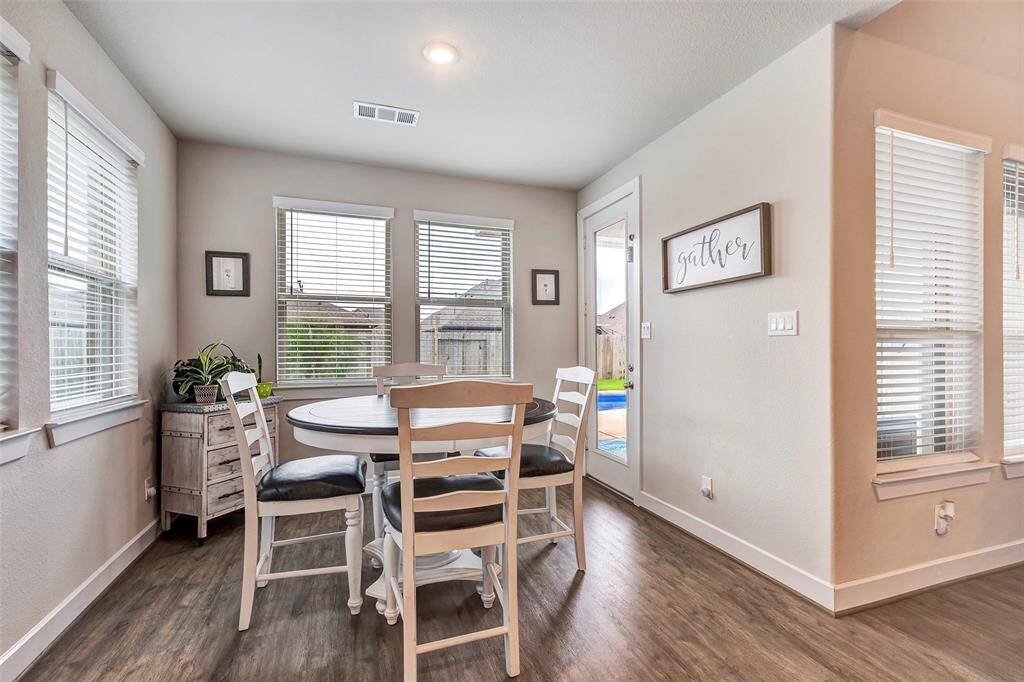 This close-up view of the breakfast room showcases its cozy atmosphere, with large windows offering plenty of natural light and direct access to the backyard for easy indoor-outdoor living.