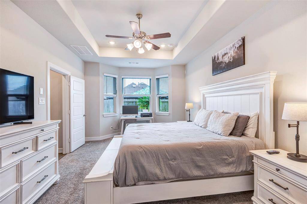 Relax in the spacious main bedroom, featuring a stunning tray ceiling and soft, carpeted floors that add warmth and comfort to the space.