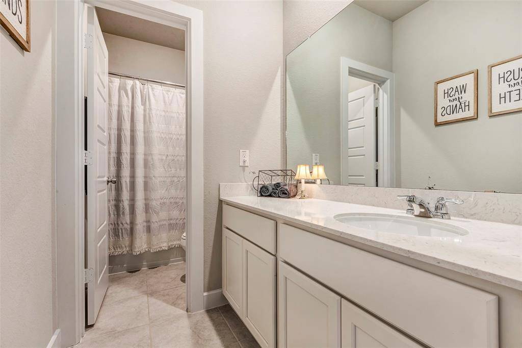 Functional and stylish, the secondary bathroom features a tub and shower combo, a single sink, and a large vanity mirror.