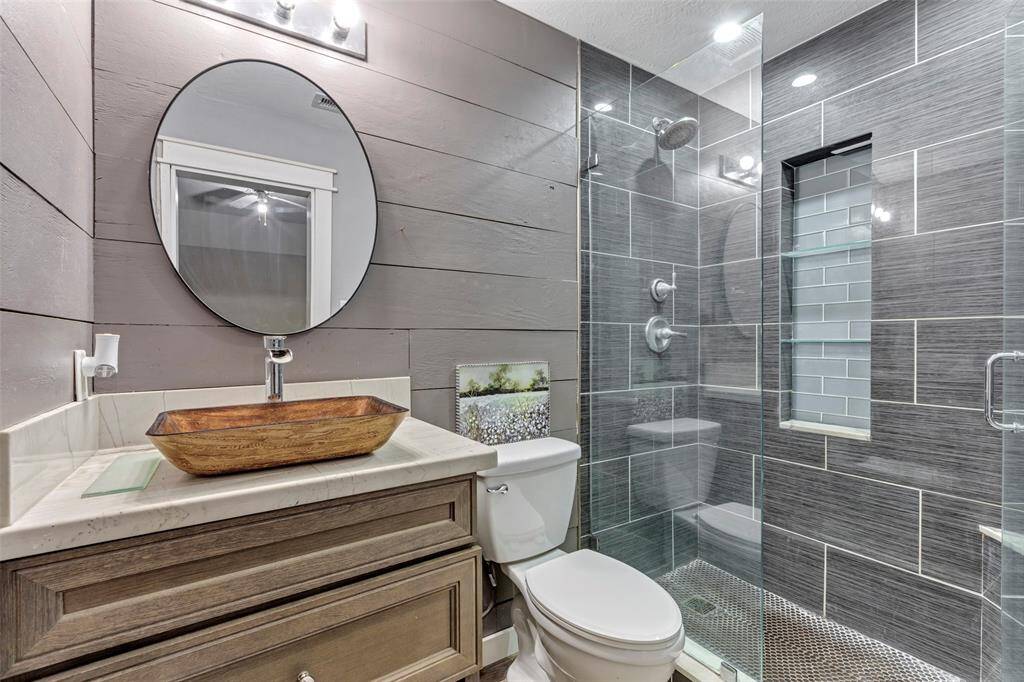 The primary bathroom features a sleek glass-enclosed shower, complemented by elegant wall tiles that add a touch of luxury and sophistication.