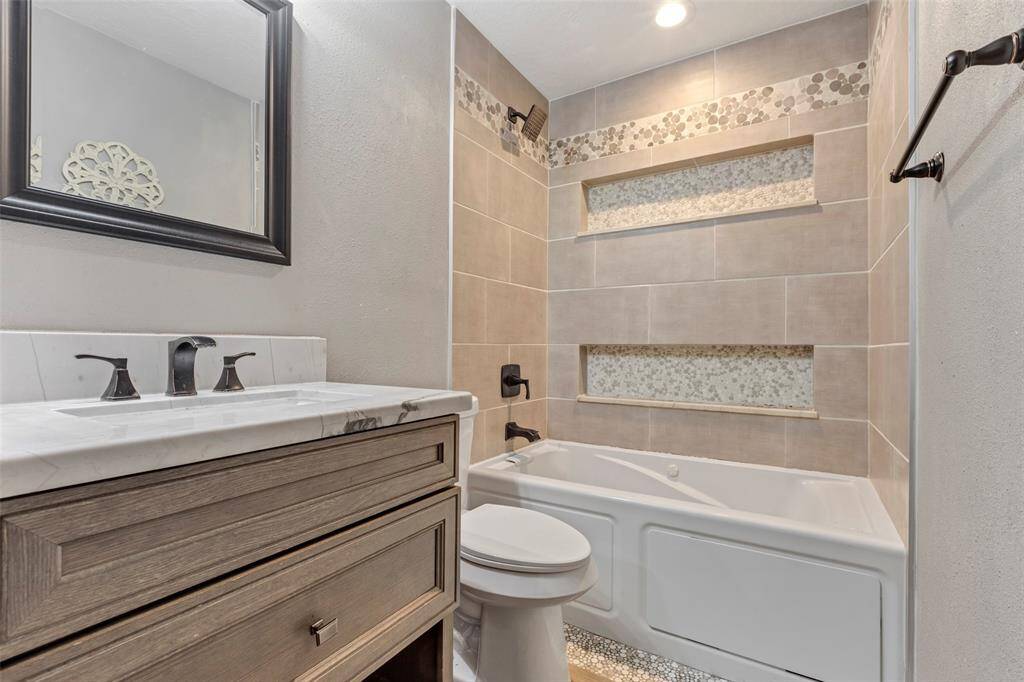 This secondary bedroom features a full bathroom with a tub-and-shower combo and a single sink, offering both comfort and convenience.