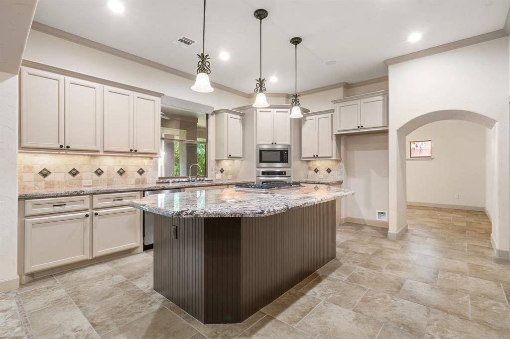 Spacious kitchen has an island with a gas cooktop and plenty of seating capacity.
