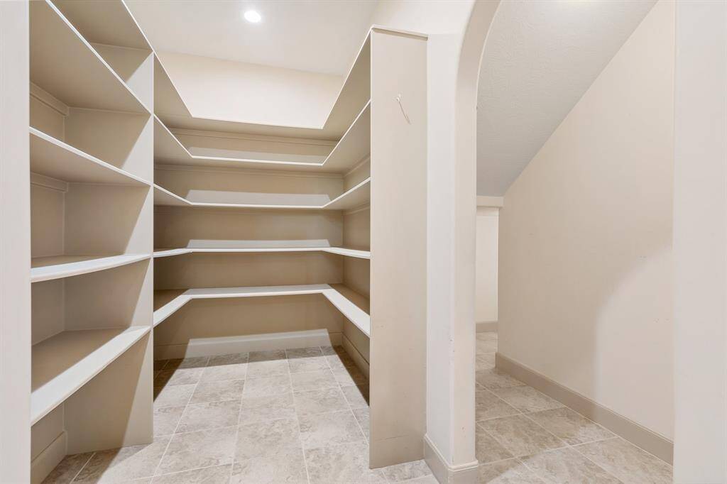 Oversized pantry with lots of shelving and additional storage room attached.