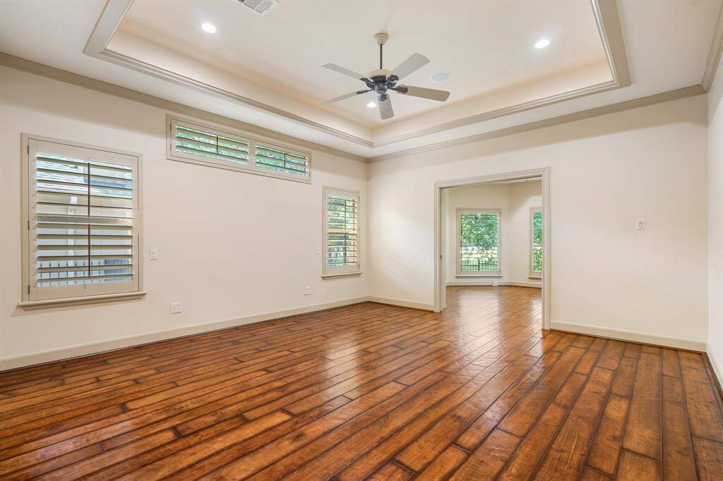 Primary bedroom on the 1st floor has plantation shutters, a tray ceiling and attached sunroom or 2nd study. All with hardwood flooring.