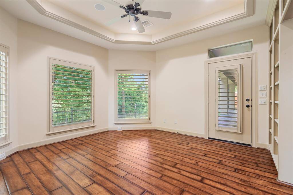 Sunroom off of the primary bedroom has a wall of built-ins, tray ceiling and a door to your private covered patio.