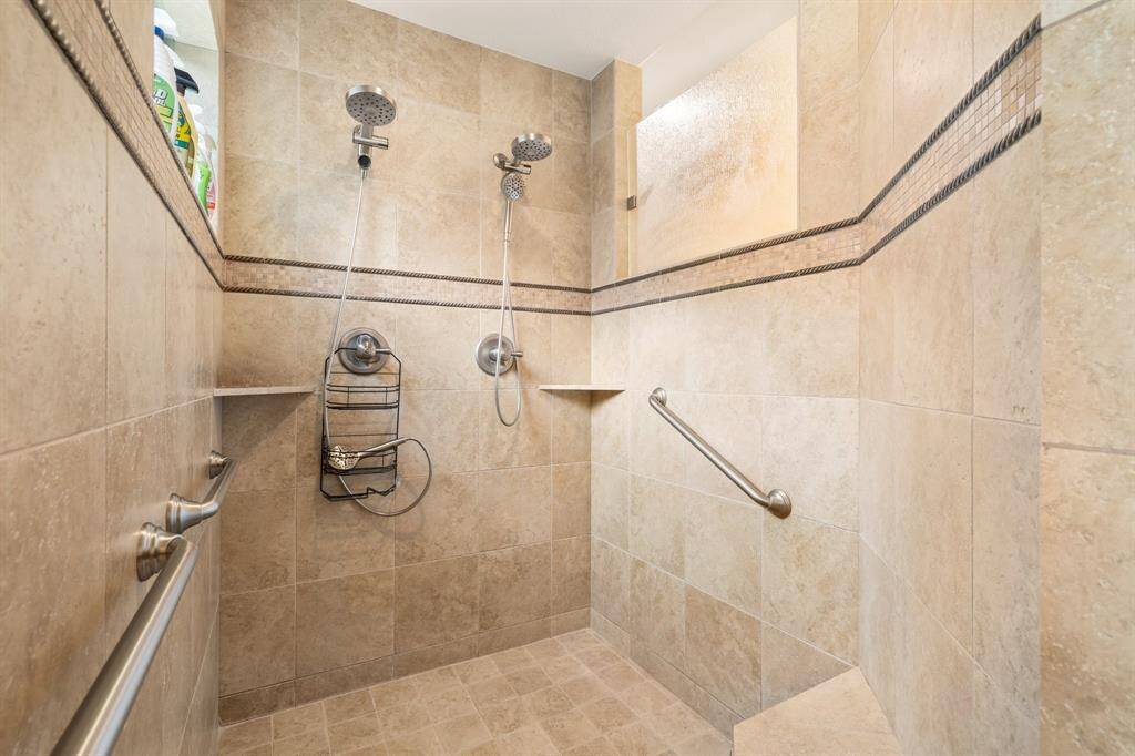 Huge primary shower with double shower heads and seating bench.