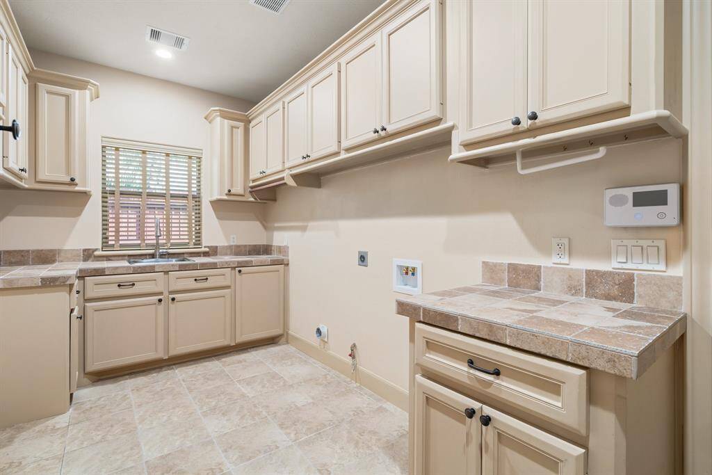 Laundry room has an abundance of cabinets and plenty of space for an extra refrigerator if desired.