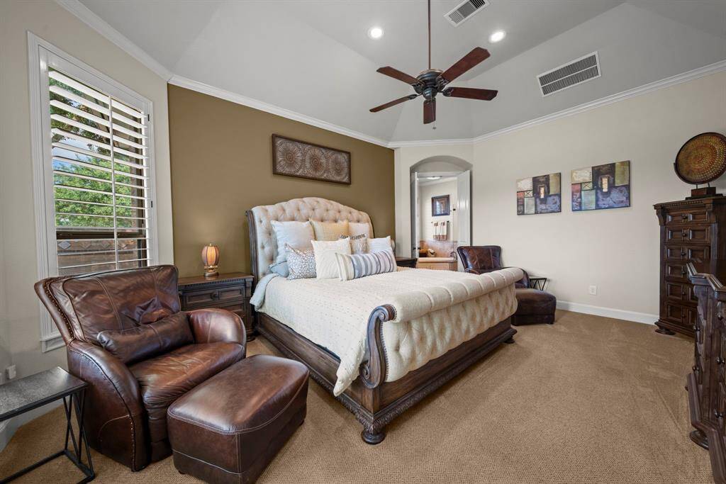 Elegant primary suite with carpet and windows overlooking the backyard
