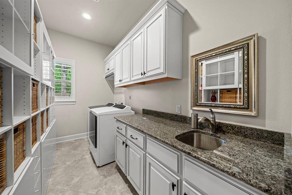 Oversized utility room with granite counters, sink, cabinet storage and room for freezers, fridge or shelves