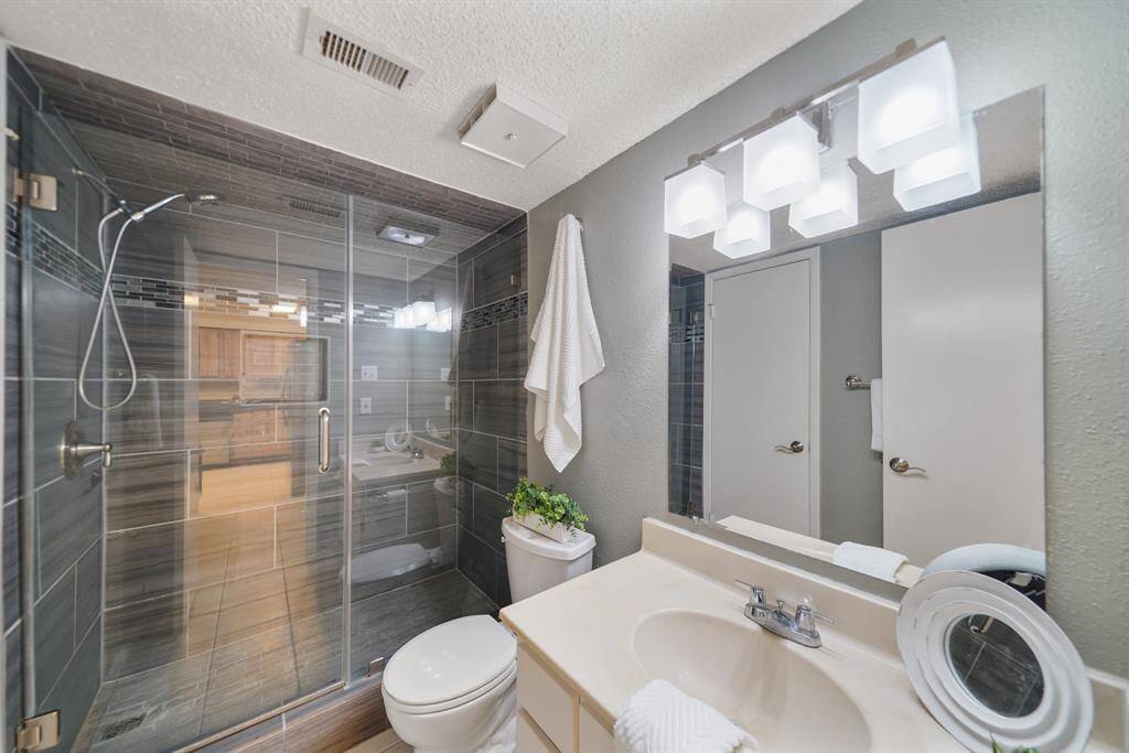 The dressing area opens to a water closet with a secondary vanity & sink with wall mounted mirror & lighting.