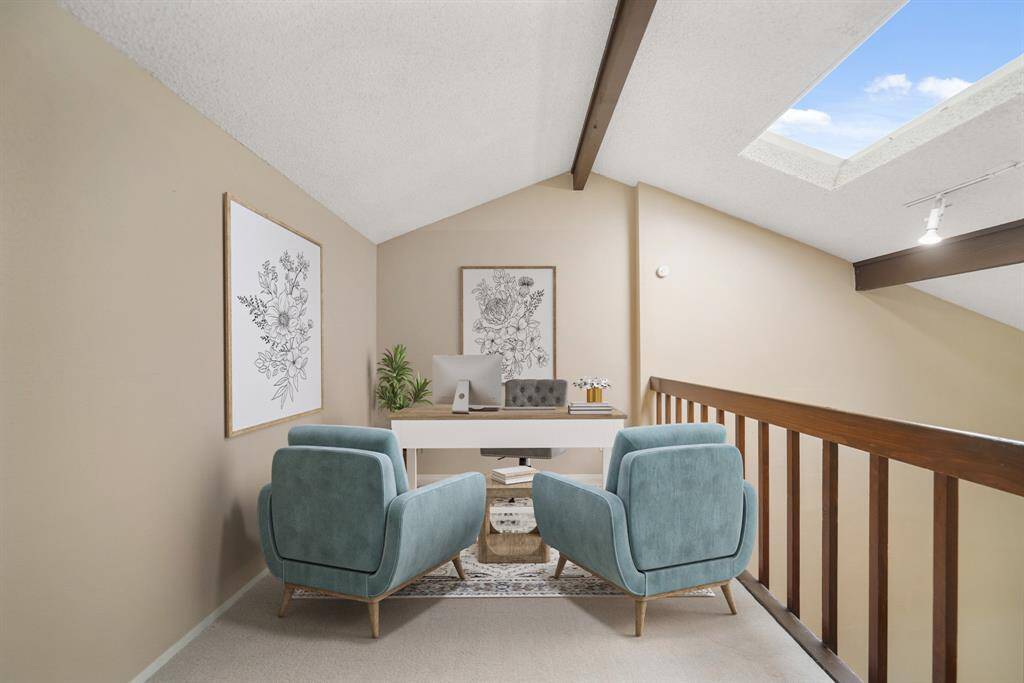 The loft area includes a high ceiling with wood-stained decorative beams, balcony views of the dining &living rooms below & new carpet. This photo has been virtually staged.