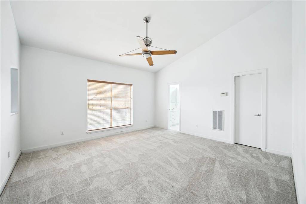 Primary bedroom has high ceilings and new carpet