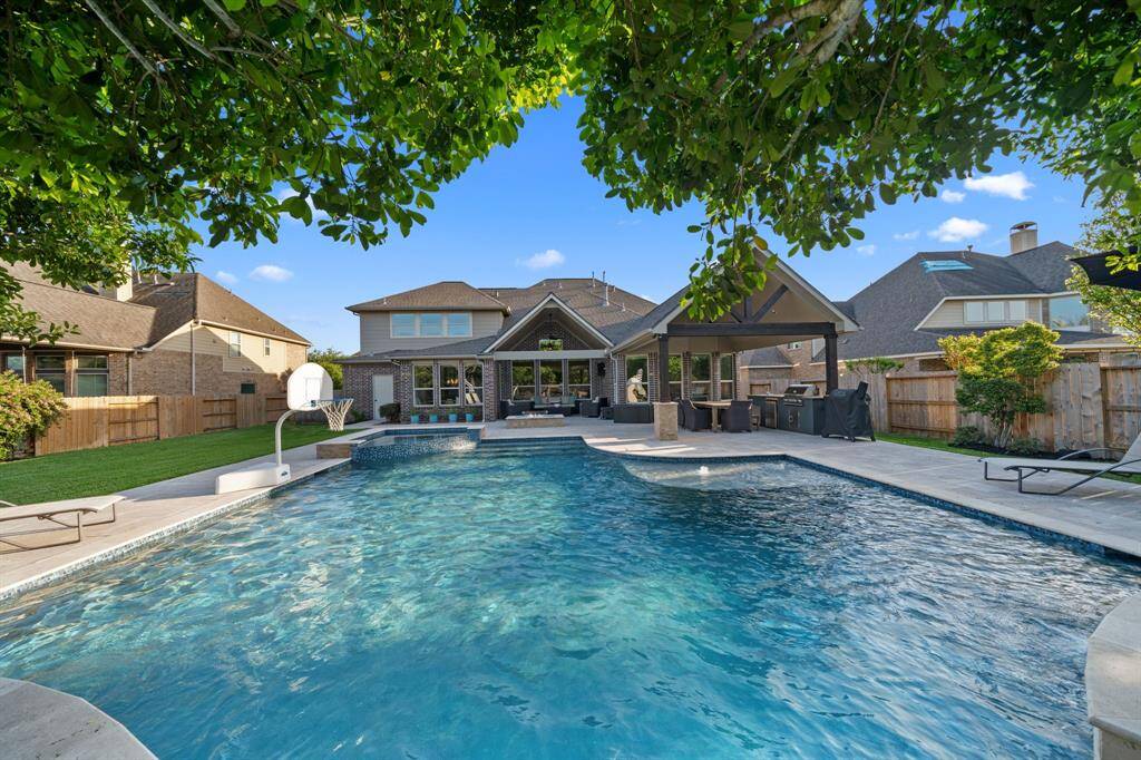 26330 Andrew Arbor Court features is a beautiful backyard oasis featuring a sparkling pool, spa, covered patio, outdoor kitchen, and lush landscaping.