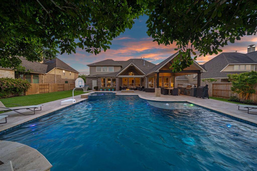 In twilight, the pool area is bathed in a soft, fading light that casts purple and orange reflections across the water's surface, creating a serene and calming atmosphere.
