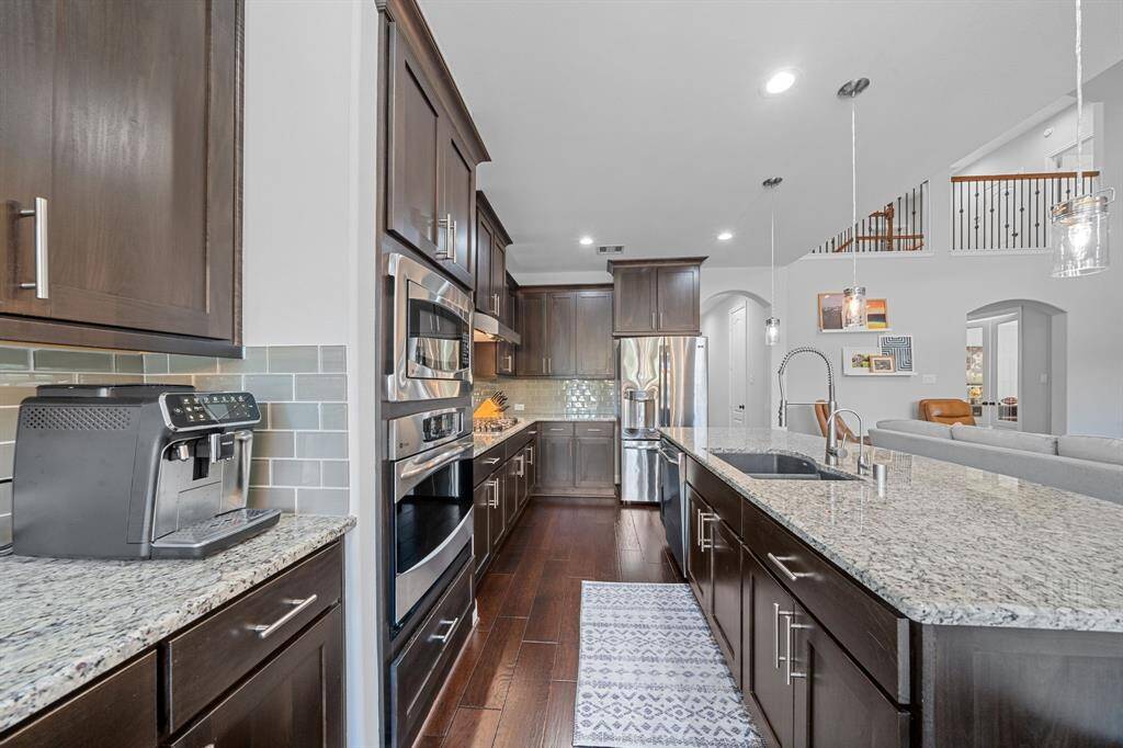 This gourmet kitchen boasts rich cabinetry, granite countertops and a large island—plus a walk-in pantry and adjacent laundry room plumbed for an ice maker or sink.