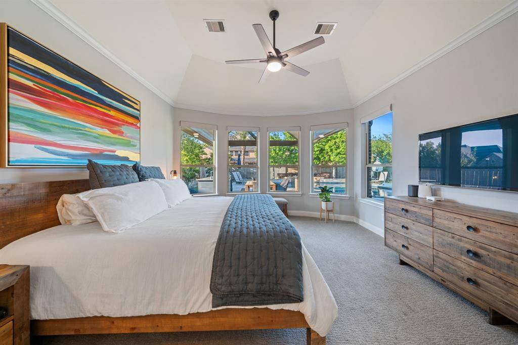 The primary bedroom on the first floor offers ample space with carpeted flooring and elegant crown molding.