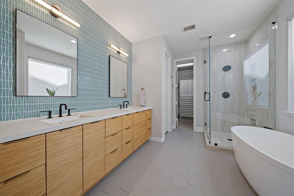 The bathrooms feature two sinks set in beautiful quartz countertops. Throughout the home, all toilets and sinks have been updated to modern standards. The light green tiles of the on which the new mirrors are mounted enhance the white oak wood of the drawers of the cabinet. These are soft-close and electrical drawers for maximum comfort.