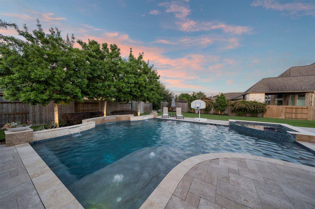 The pool features elegant tile finishes, an efficient in-floor cleaning system, soothing water features, and a sun shelf that gradually deepens to 7 feet for versatile enjoyment.