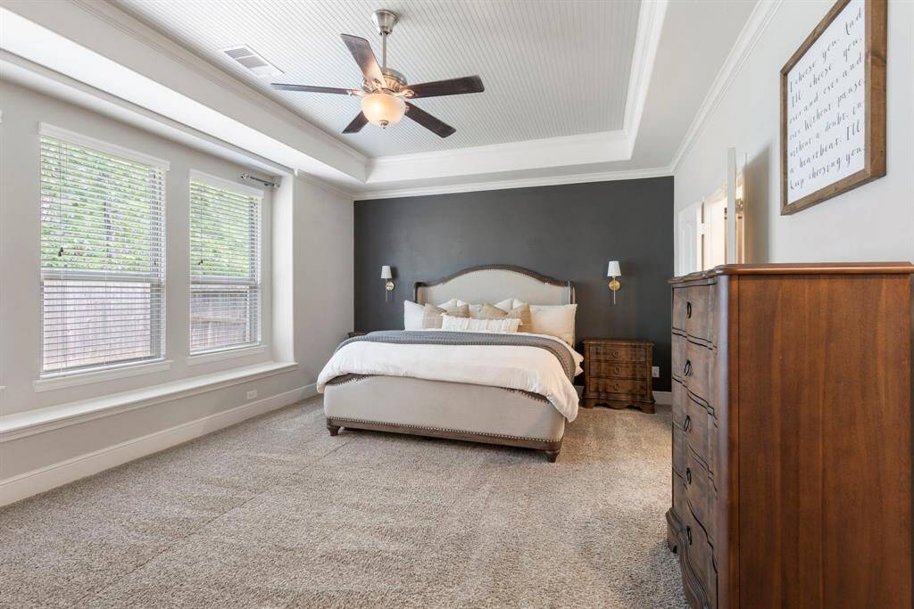 The primary bedroom is welcoming and serene, featuring a wall of windows that fills the space with natural light and offers peaceful views of the outdoors.
